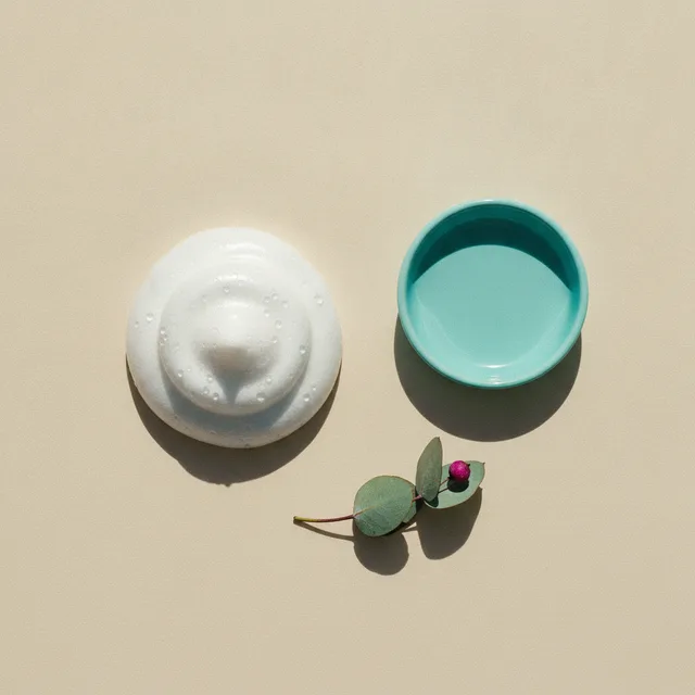 Grooming foam and a turquoise ceramic dish on cream paper